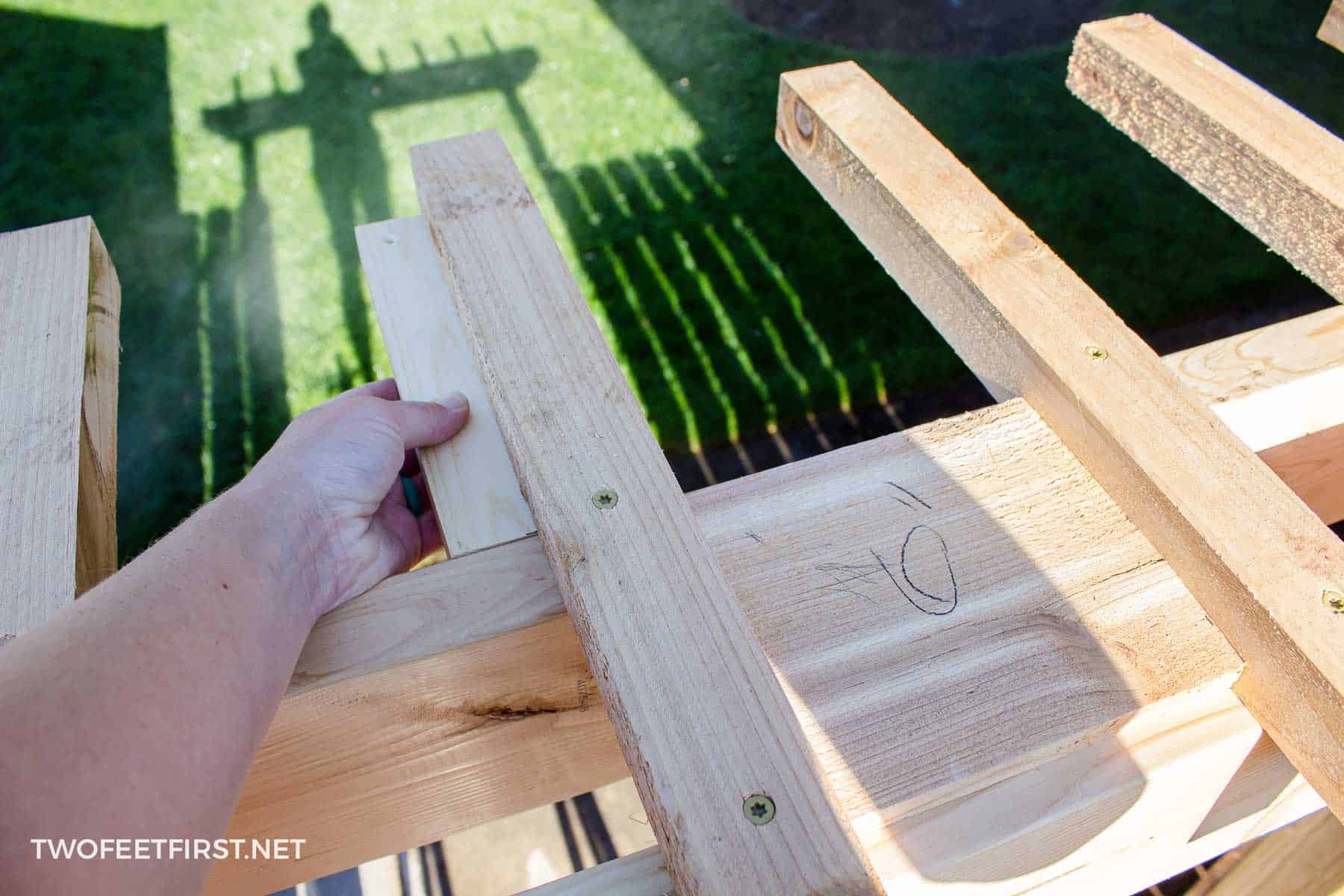 Adding top trim boards to gate pergola using template to make the spacing the same