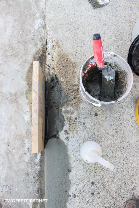 applying concrete to chipped step using wood board to shape the concrete