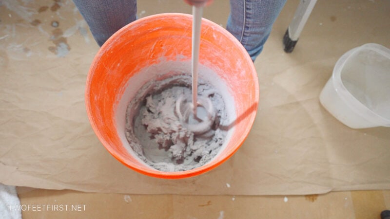 mixing grout in orange bucket with drill attachment