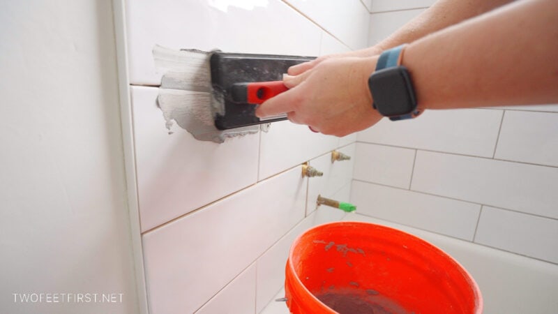 placing grey grout on bathroom tile walls