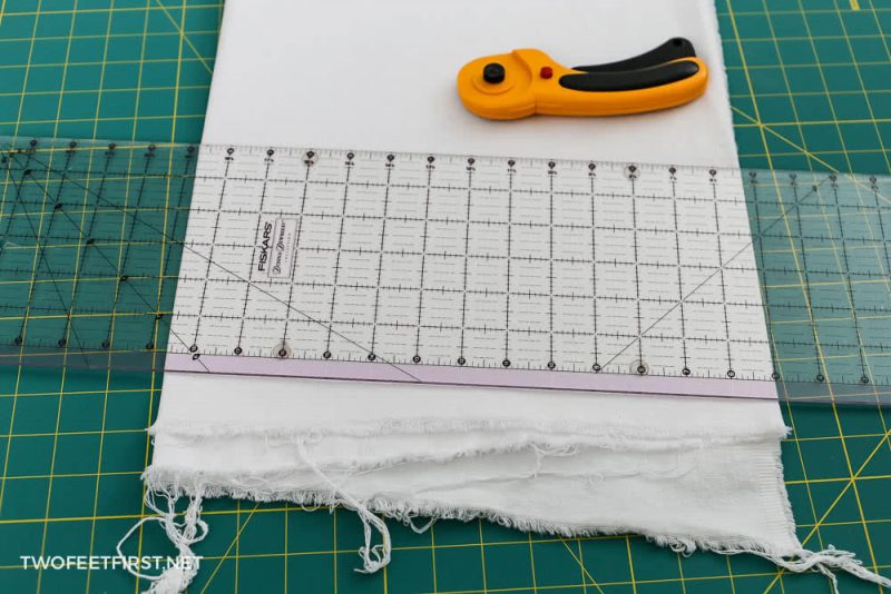 white fabric on cutting mat with rotary cutter and ruler